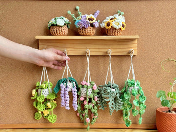 Crocheted hanging plant pots with colorful flowers on a wooden shelf